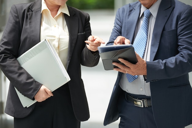 Bijgesneden afbeelding van succesvolle zakenpartners wijzend op tabletcomputer bij het bespreken van details van het contract