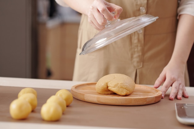 Bijgesneden afbeelding van vrouw die linker stuk deeg bedekt met deksel na het maken van ronde broodjes