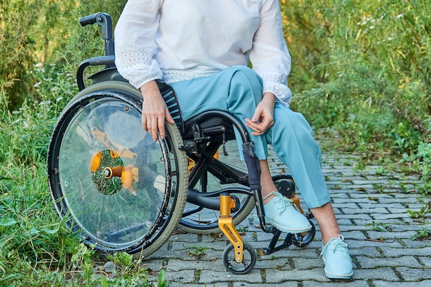 Bijgesneden afbeelding van vrouw in rolstoel wandelen in park buitenshuis, zonnig herfstweer.