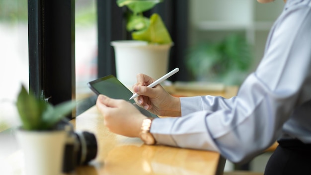 Bijgesneden afbeelding van vrouwelijke accountant die digitale tablet en styluspen gebruikt om gegevens te berekenen en te analyseren.