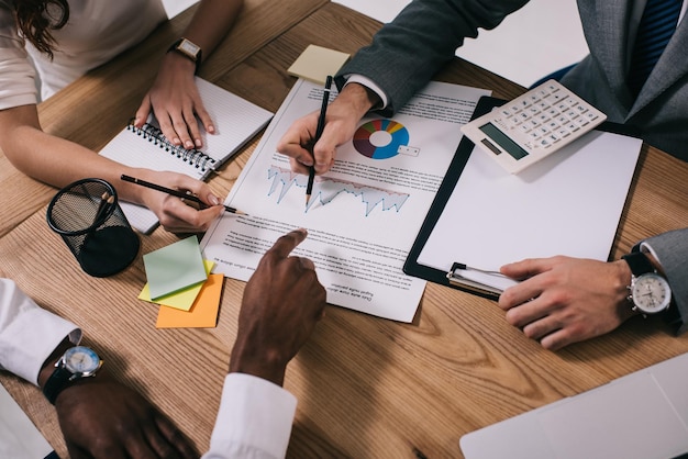 Bijgesneden afbeelding van zakelijke collega's die papierwerk doen terwijl ze aan tafel zitten