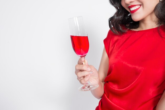 Bijgesneden afbeeldingen van jonge vierende Aziatische vrouw in rode jurk met wijnglas.
