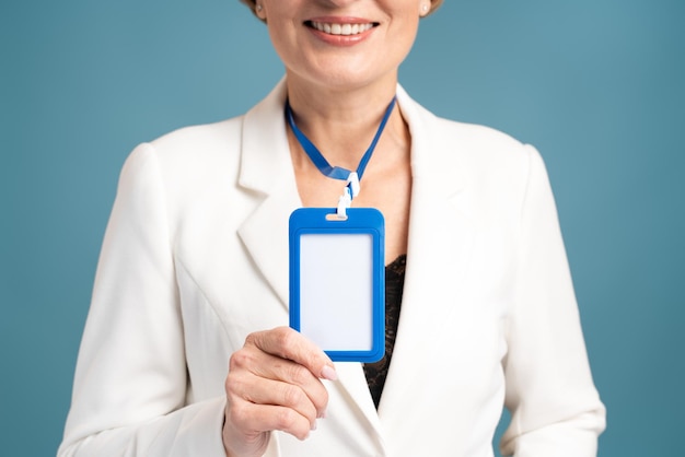 Bijgesneden beeld van de vrouw die haar lege verticale ID-badgemodel toont, geïsoleerd. Identiteitslabel van de persoon. Senior vrouw in hemduniform met lege ID-kaart mock up