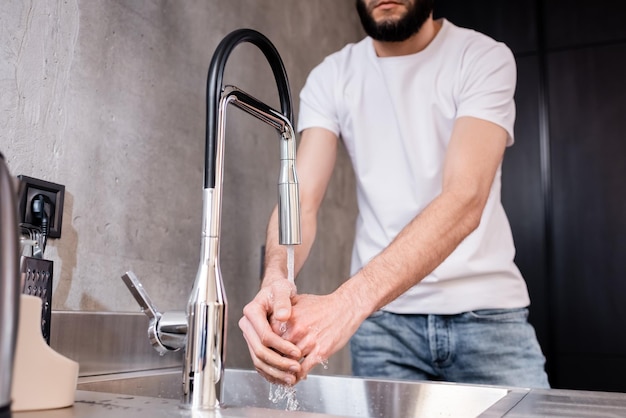 Bijgesneden beeld van man die handen wast in de keuken