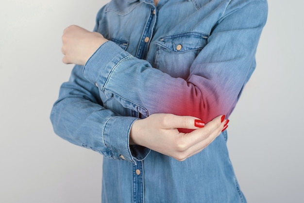 Bijgesneden close-up foto van ongelukkig lijden aan pijn dame aanraken van elleboog geïsoleerd op grijze achtergrond kopie-ruimte dragen casual denim jeans kleding