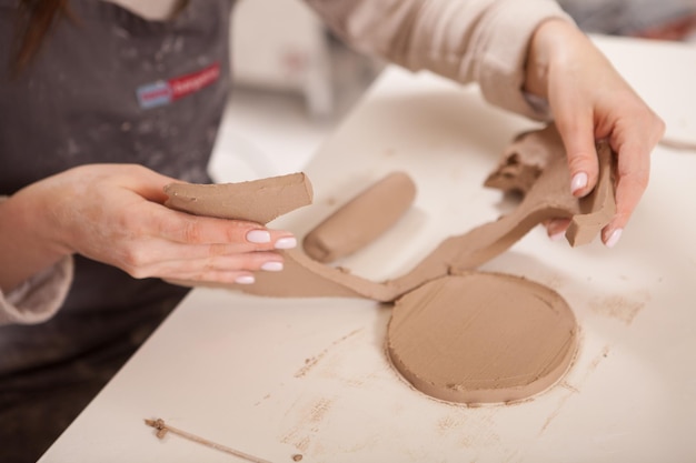 Bijgesneden close-up van een vrouw die met klei werkt in een keramiekworkshop