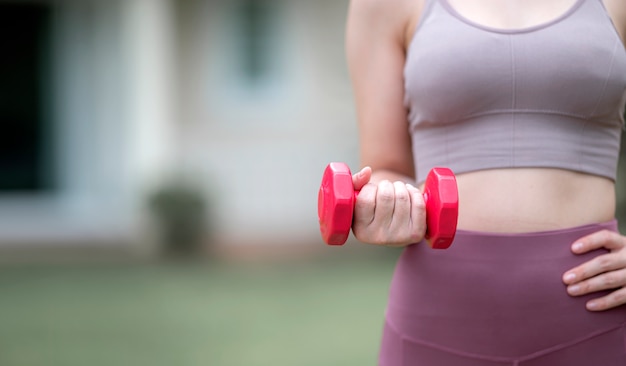 Bijgesneden foto van blanke vrouw training met rode halter buitenshuis. Kopieer ruimte.