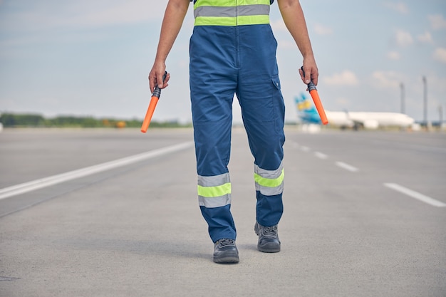 Bijgesneden foto van een blanke man in veiligheidsoverall met een paar rangeerstokken