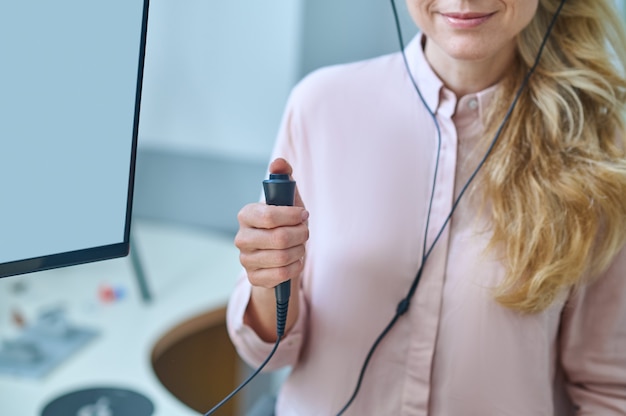 Bijgesneden foto van een blonde vrouw die op de knop van de responsschakelaar drukt tijdens de audiometrietest