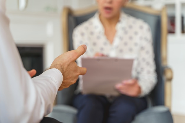 Bijgesneden foto van een vrouwelijke psycholoog zittend in een fauteuil voor haar cliënt