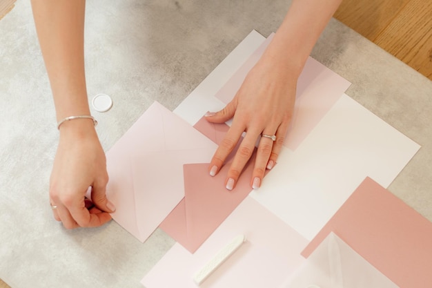 Bijgesneden foto van vrouw handen maken roze compositie wieden uitnodiging papier inwikkeling envelop zegel...