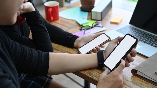 Bijgesneden geschoten man die een smartphone vasthoudt en informatie deelt met zijn collega.