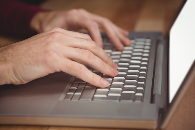 Bijgesneden hand van de man aan het werk op laptop