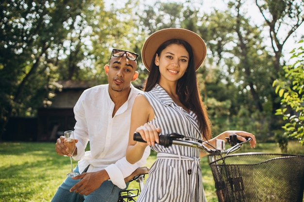 Bijgesneden horizontaal portret van twee jonge mensen, man en vrouw, zittend op de fiets in de tuin