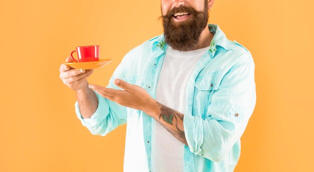 Bijgesneden ongeschoren man in shirt met koffie op gele achtergrond drank