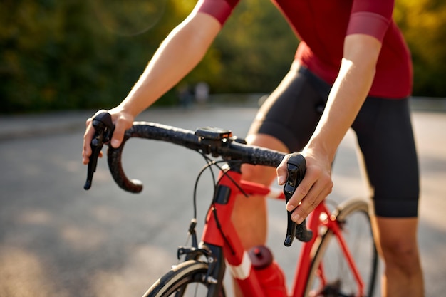 Bijgesneden onherkenbare man gekleed in sportieve wielerkleding fietsen op asfalt buiten de stad...