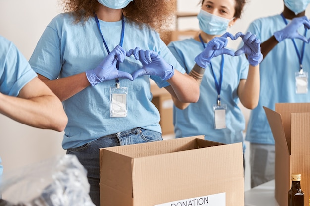 Bijgesneden opname van diverse mensen met blauwe uniforme beschermende maskers en handschoenen met liefdeshart