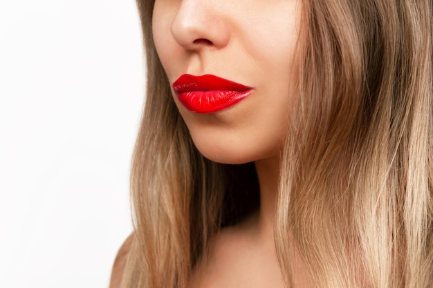 Bijgesneden opname van een jonge, mooie blanke blonde vrouw met glanzende rode lippenstift op haar lippen