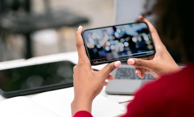 Bijgesneden opname van een jonge vrouw die video kijkt op haar smartphone in horizontale weergave