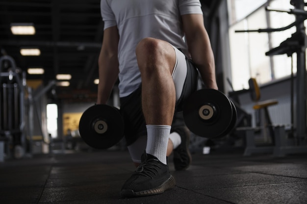 Bijgesneden opname van een sportman die gewogen lunges doet in de sportschool