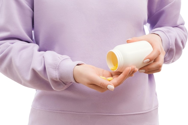 Bijgesneden opname van een vrouw in een oversized sweatshirt met lavendel en giet gele pillen uit de grote witte fles