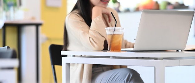 Bijgesneden opname van jonge vrouwelijke ondernemer die aan haar project denkt en met een computerlaptop werkt terwijl ze in de coffeeshop zit.