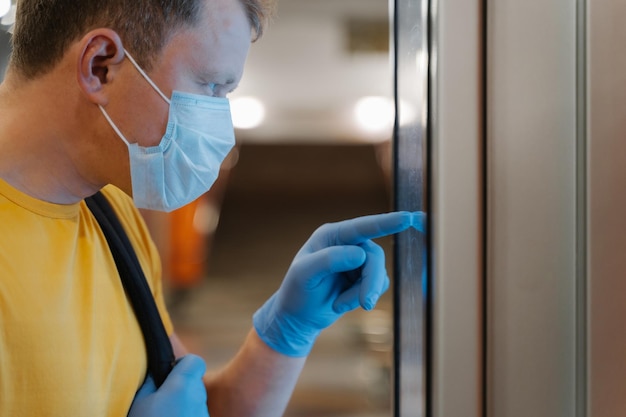 Bijgesneden opname van man draagt medisch masker en rubberen handschoenen raakt scherm van automaat in supermarkt aan, geeft om epidemische veiligheid preventie van verspreiding van coronavirus Selectieve focus