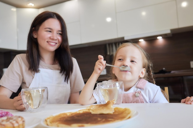 Bijgesneden opname van moeder in het rood en haar dochter met kleurrijke donuts in de keuken dieetconcept en junkfood