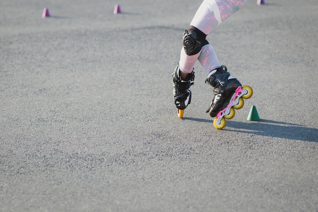 Bijgesneden opname van tiener rollerblades op asfalt, heeft proces, draagt rollerblade en bescherming op knieën