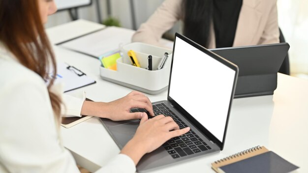 Bijgesneden opname van vrouwelijke manager die laptopcomputer gebruikt tijdens vergadering in modern kantoor