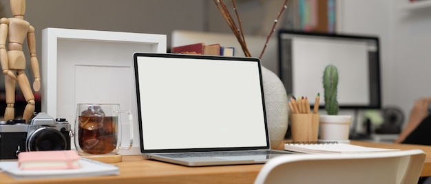 Bijgesneden schot van bureau met laptop, briefpapier, kantoorbenodigdheden en decoratie in kantoorruimte, uitknippad.