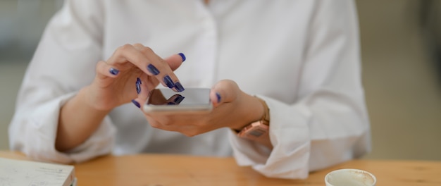 Bijgesneden schot van jonge vrouwelijke universiteitsstudent met smartphone