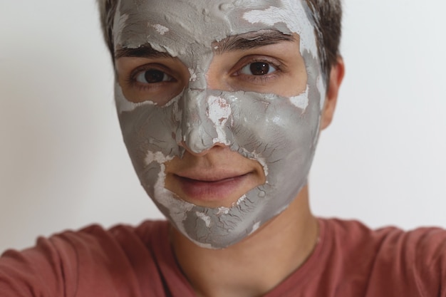 Bijgesneden schot van vrouw past grijsgroen huidverzorgingskleimasker toe op de dagelijkse schoonheidsverzorgingsroutine van het gezicht