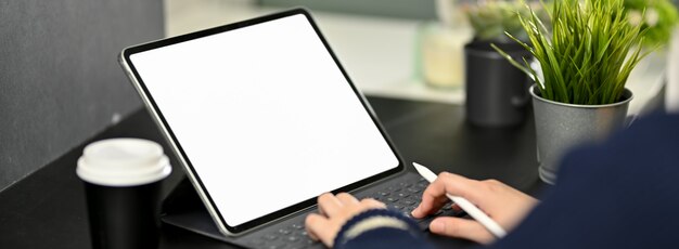 Bijgesneden schot van vrouwelijke freelancer typen op digitale tablet op zwarte tafel