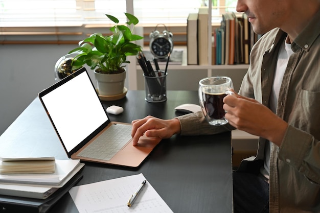 Bijgesneden shot jonge man online aan het werk met laptopcomputer thuis