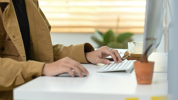 Bijgesneden shot man aan het werk met computer in kantoor aan huis.