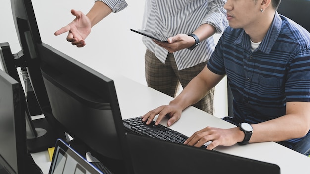 Bijgesneden shot programmeur consulting met tablet en computer op ontwikkelaar werkruimte.