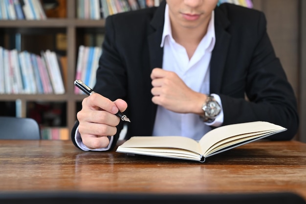 Bijgesneden shot zakenman schrijven van informatie op notebook