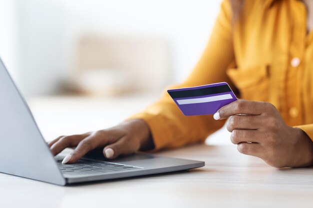 Bijgesneden van Afro-Amerikaanse vrouw met behulp van computer en creditcard