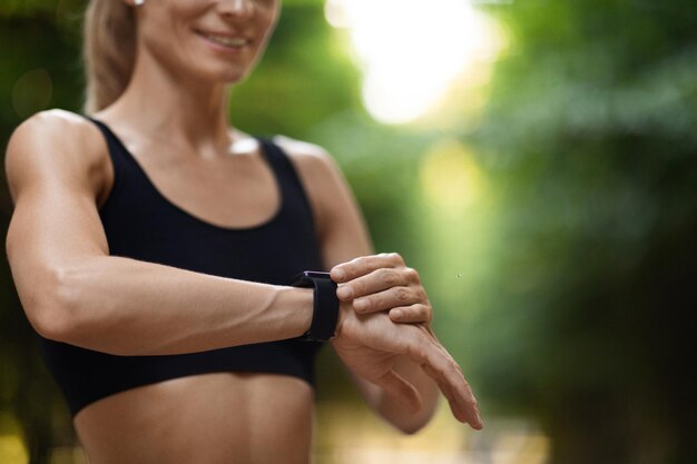 Bijgesneden van sportieve vrouw stelt haar fitnesstracker in