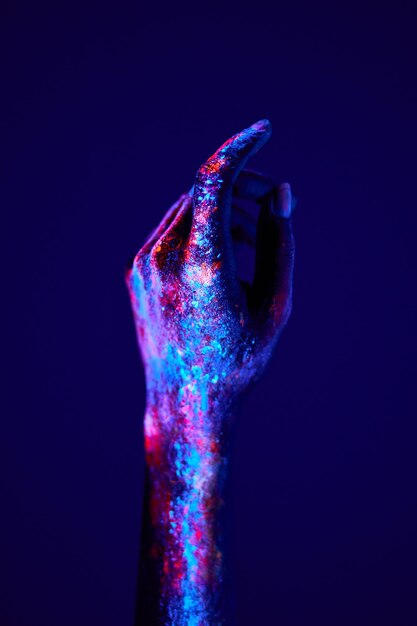 Foto bijgesneden vrouwelijke handen in rustige positie beschilderd met fluorescerend schilderij