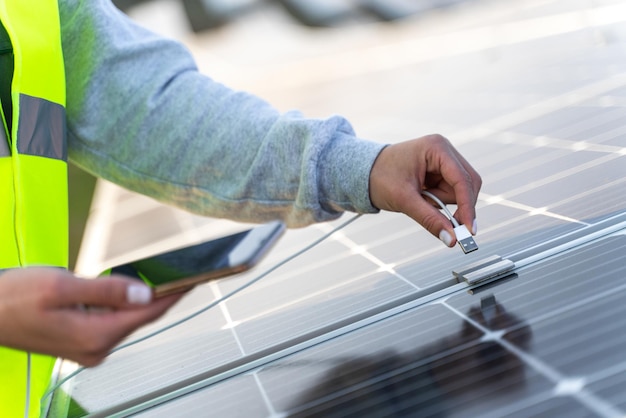 Bijgesneden weergave van de slimme vrouw die het opladen van de smartphone voorbereidt bij de zonnepanelen Een slimme bank heeft zonnepanelen op de bovenkant en kan gratis USB-apparaten opladen