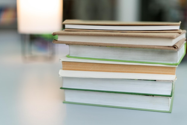 Bijgesneden weergave van de vele stapels educatieve boeken voor universiteitsexamens in de bibliotheek op een achtergrond van boekenplanken studeren concept