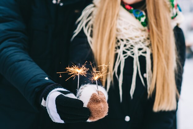 Bijgesneden weergave van het gelukkige verliefde paar dat het winterweer in het park bewondert. Ze knuffelen en hechten zich vast terwijl ze glitters vasthouden