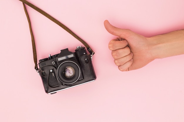 Bijgesneden weergave van man duim opdagen in de buurt van filmcamera geïsoleerd op roze