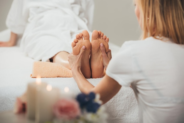 Bijgesneden weergave van masseur die voetmassage doet aan volwassen vrouw in spa