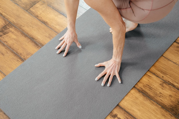 Bijgesneden weergave van volwassen vrouw die yoga of pilates doet op mat