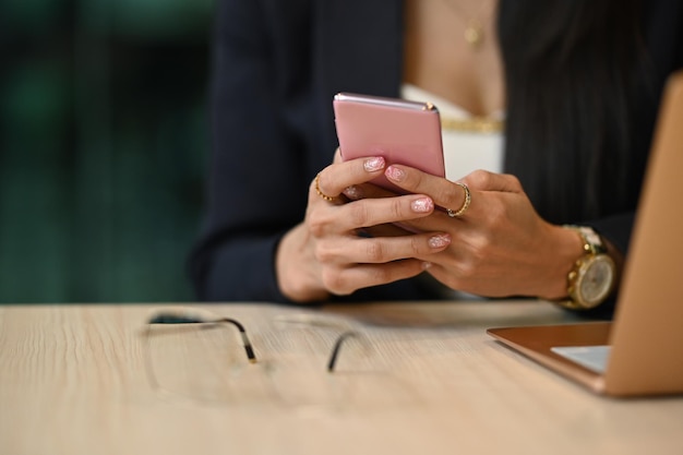 Bijgesneden weergave van werkende vrouw die mobiele telefoon gebruikt om te communiceren op sociale media