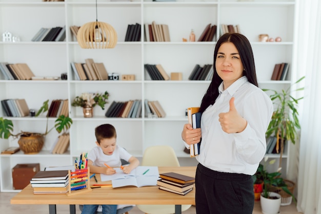 Bijlesdocent behandelt de kleuter met een laptop, een echt interieur, het concept van kindertijd en leren