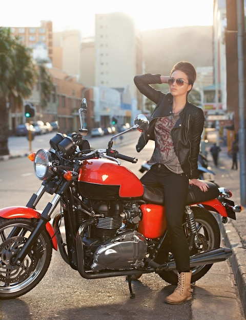 Bike fashion and woman in city with sunglasses for travel transport or road trip as rebel Leather asphalt and model with attitude on classic or vintage motorcycle for transportation or journey